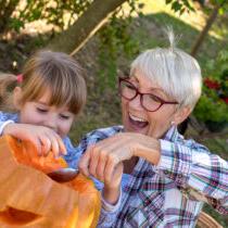 grandparent and grandchild carving jack-o-lantern